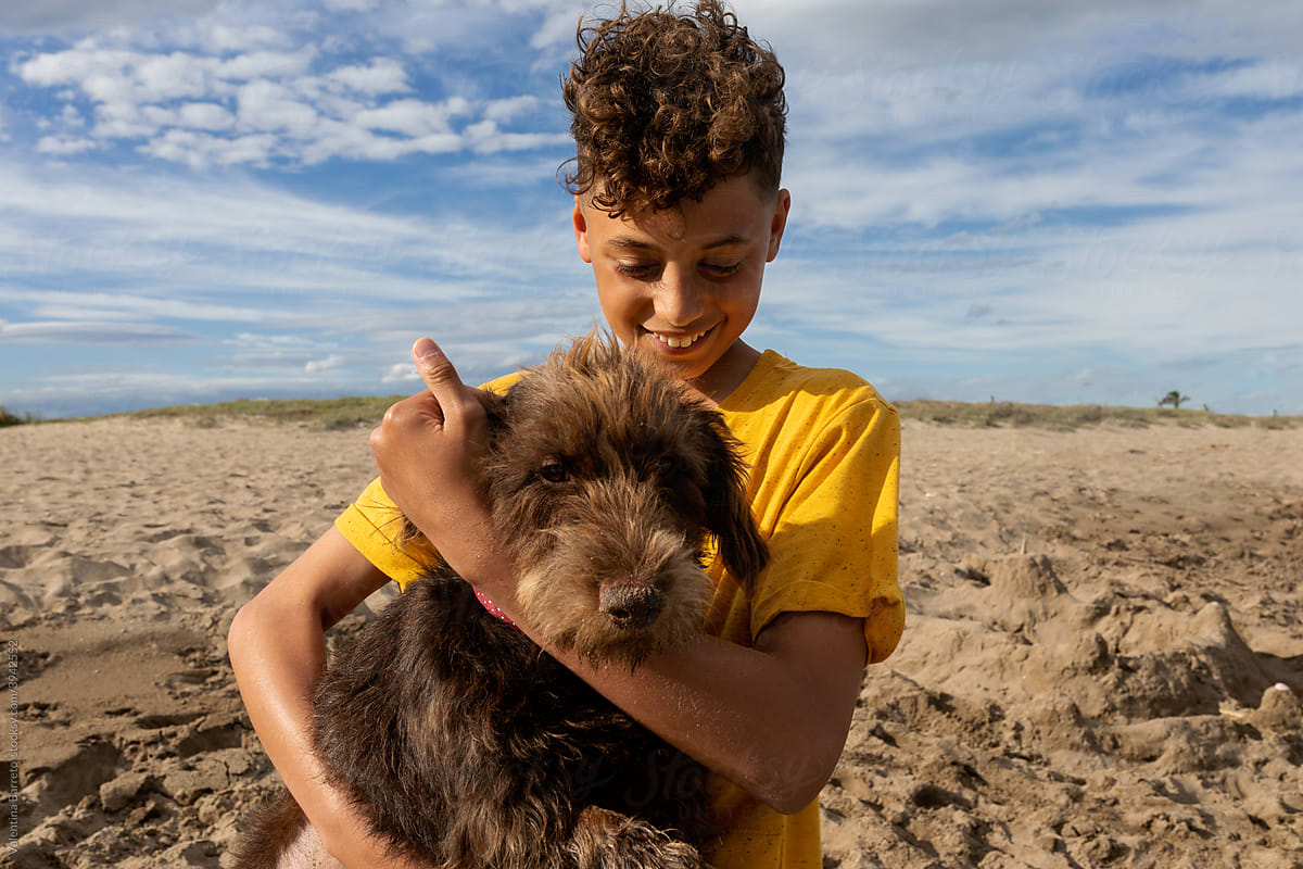 Teen boy carrying his pet at the beach