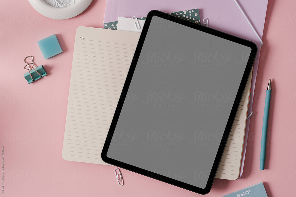 Tablet with notebooks and stationery in pink work table