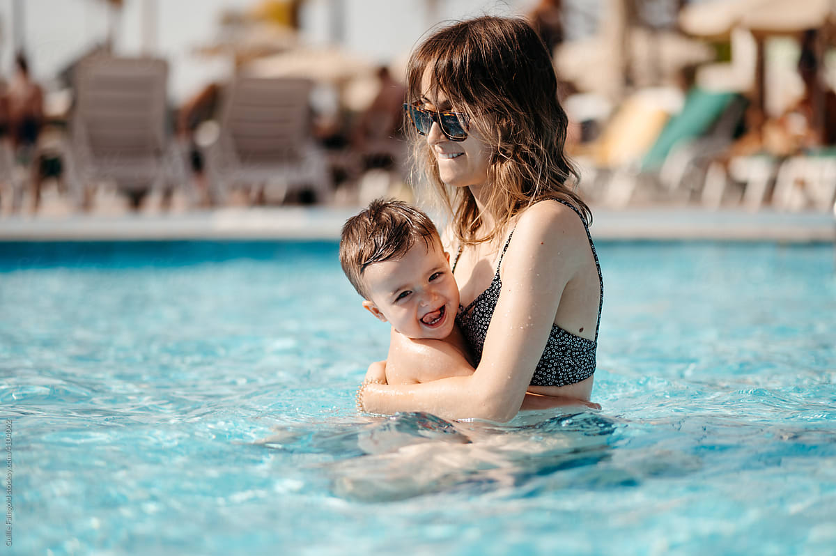 Cute toddler hugging mom in pool.