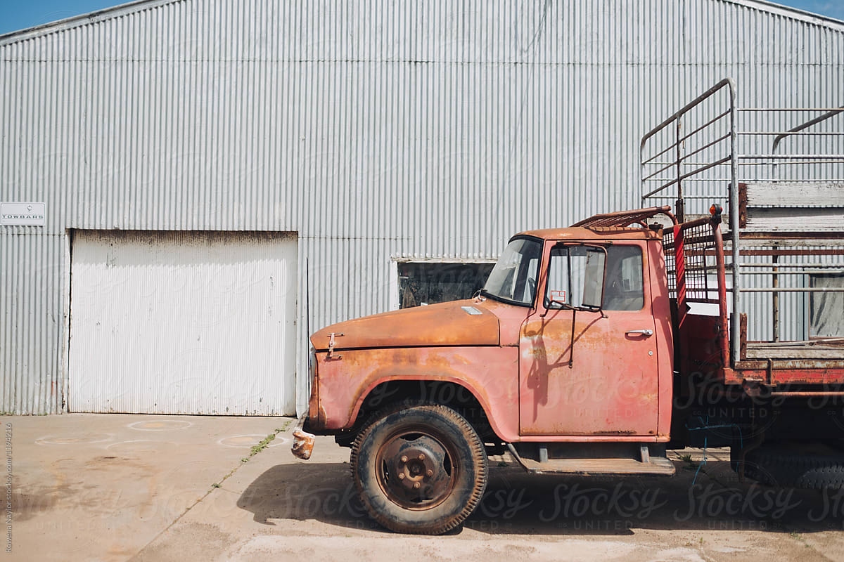 VIntage red faded truck parked against farm shed