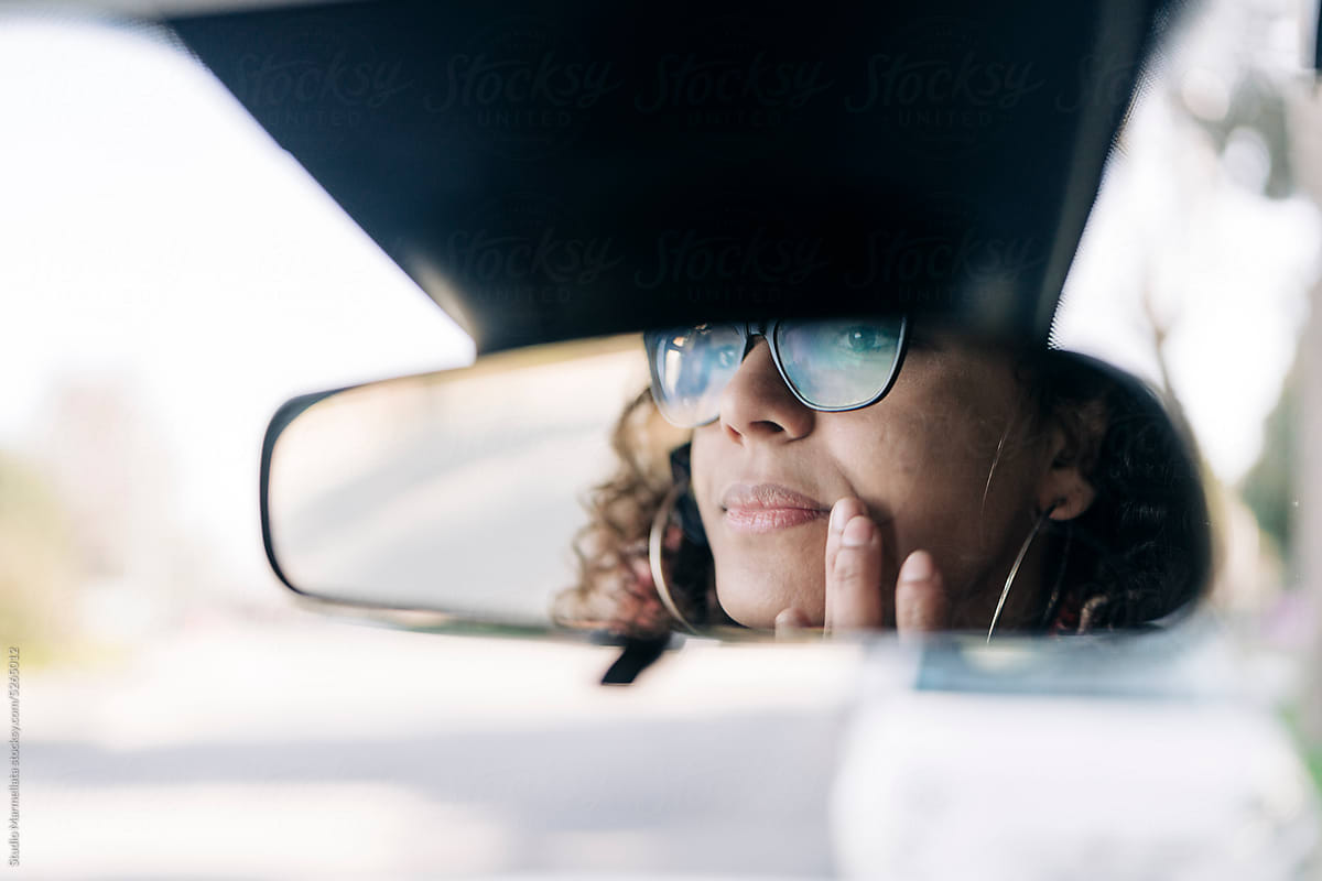 Woman looking in sun rear mirror