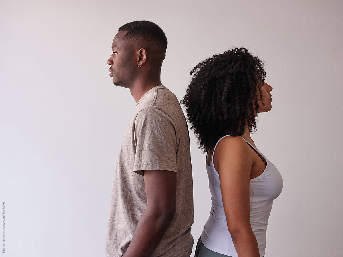 Black couple standing back to back at home