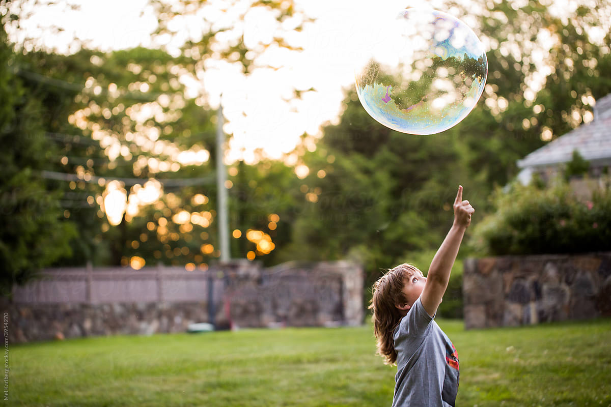 Young boy playing with bubbles in backyard