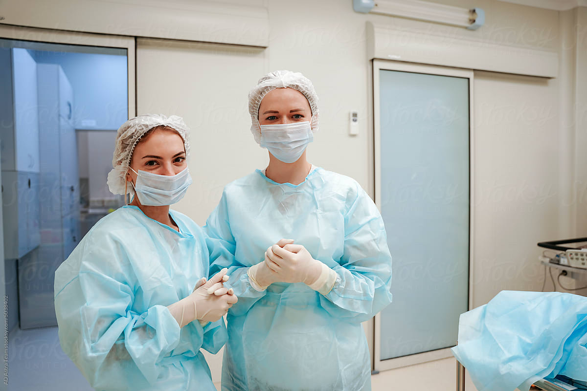 The surgeon and the intern are standing in the operating room