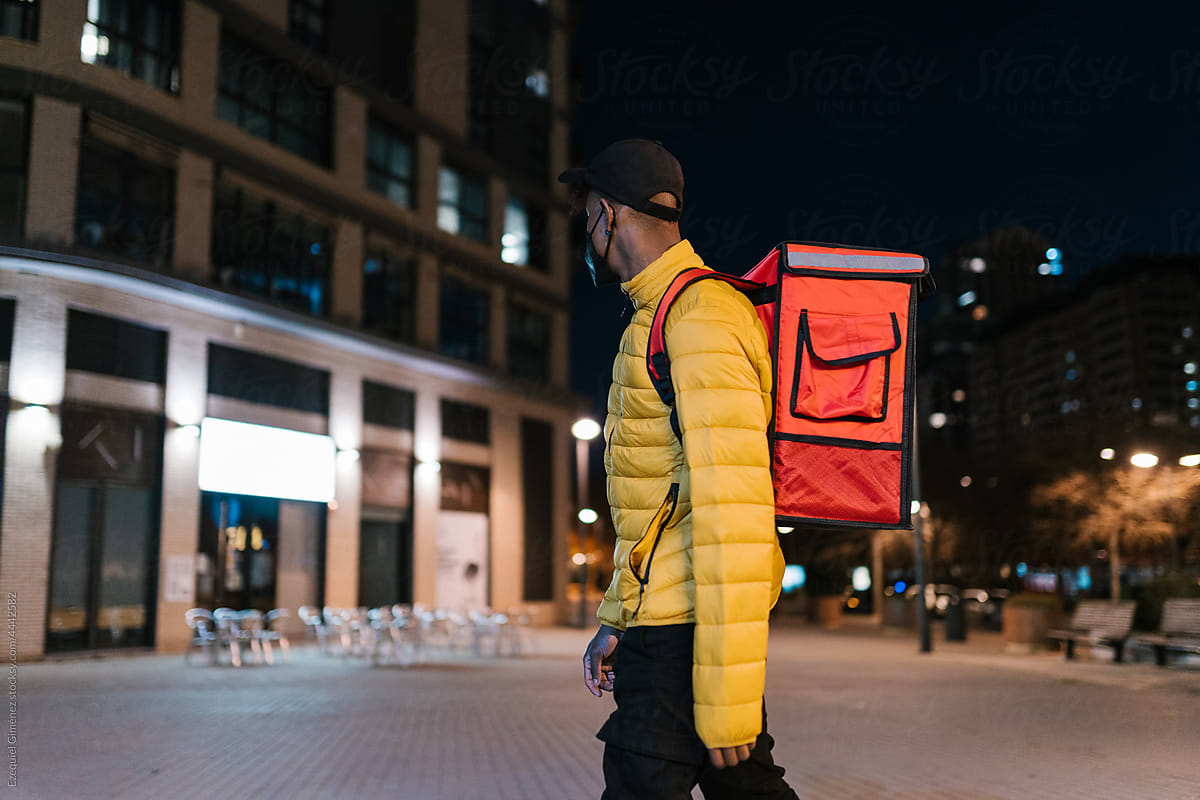 Unrecognizable delivery man walking in city at night