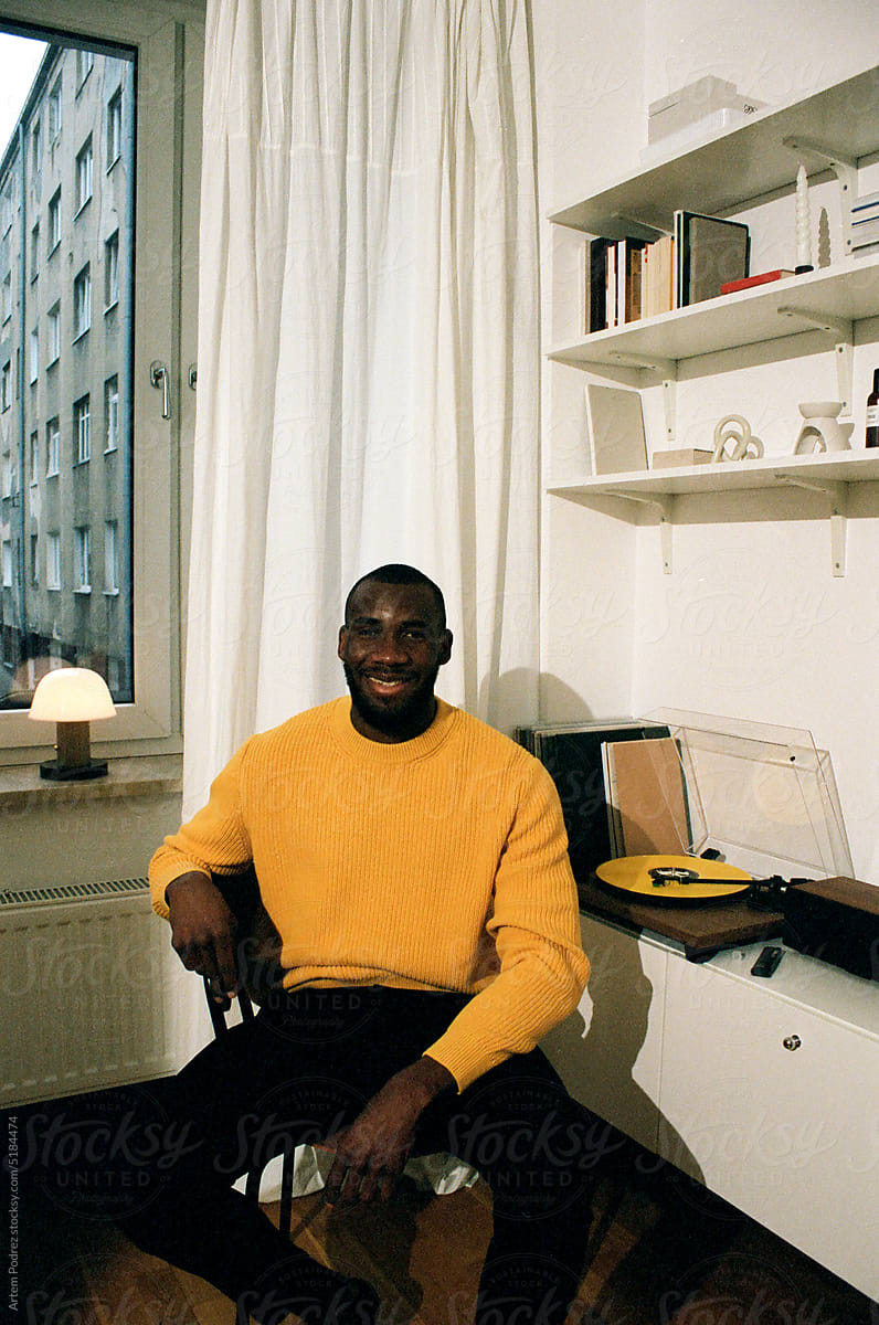 Film photo portrait of a black man on a chair in a yellow sweater