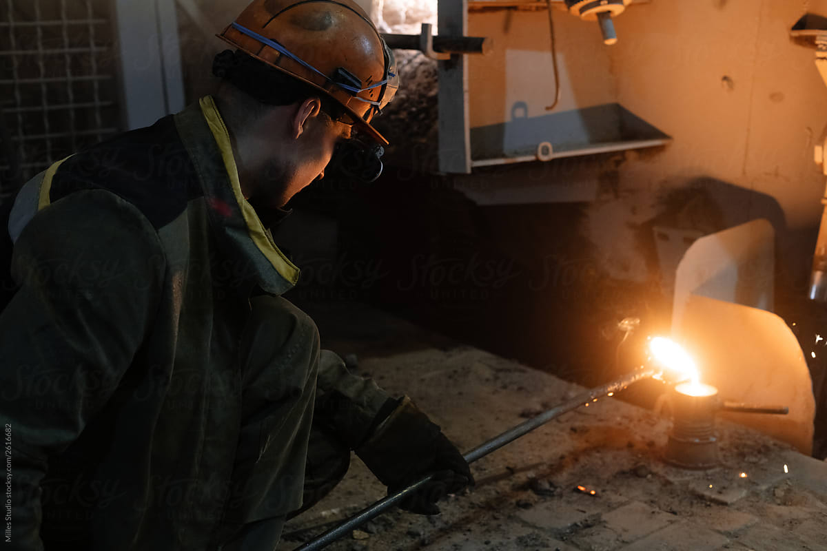 Foundry worker pouring hot metal in mold