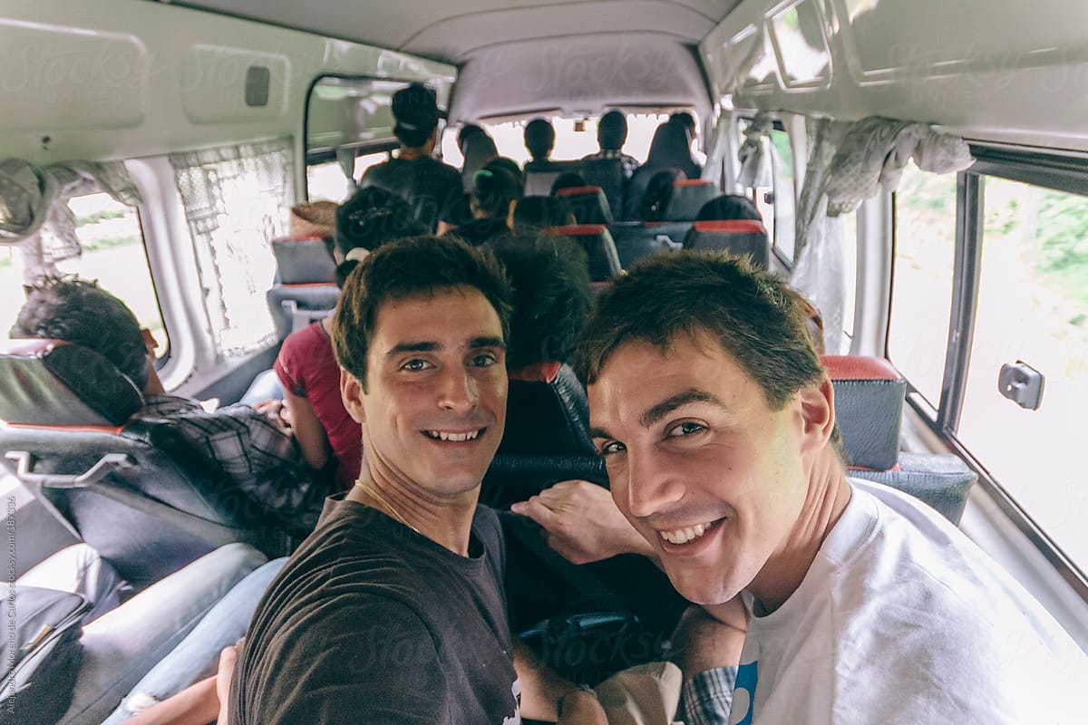 Two male friends inside a bus full of people on travel