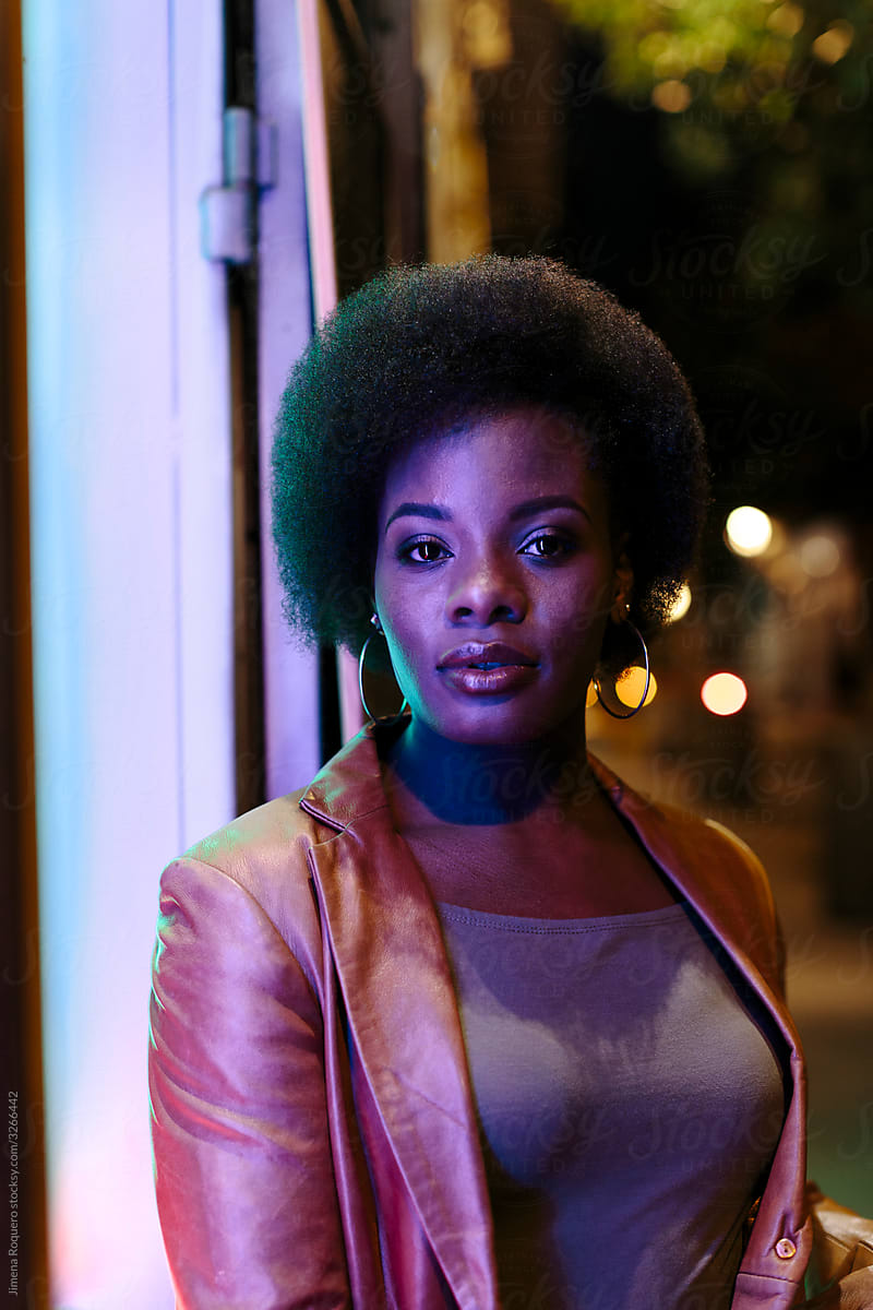 Portrait of attractive Woman with afro hair at night in the street looking at camera