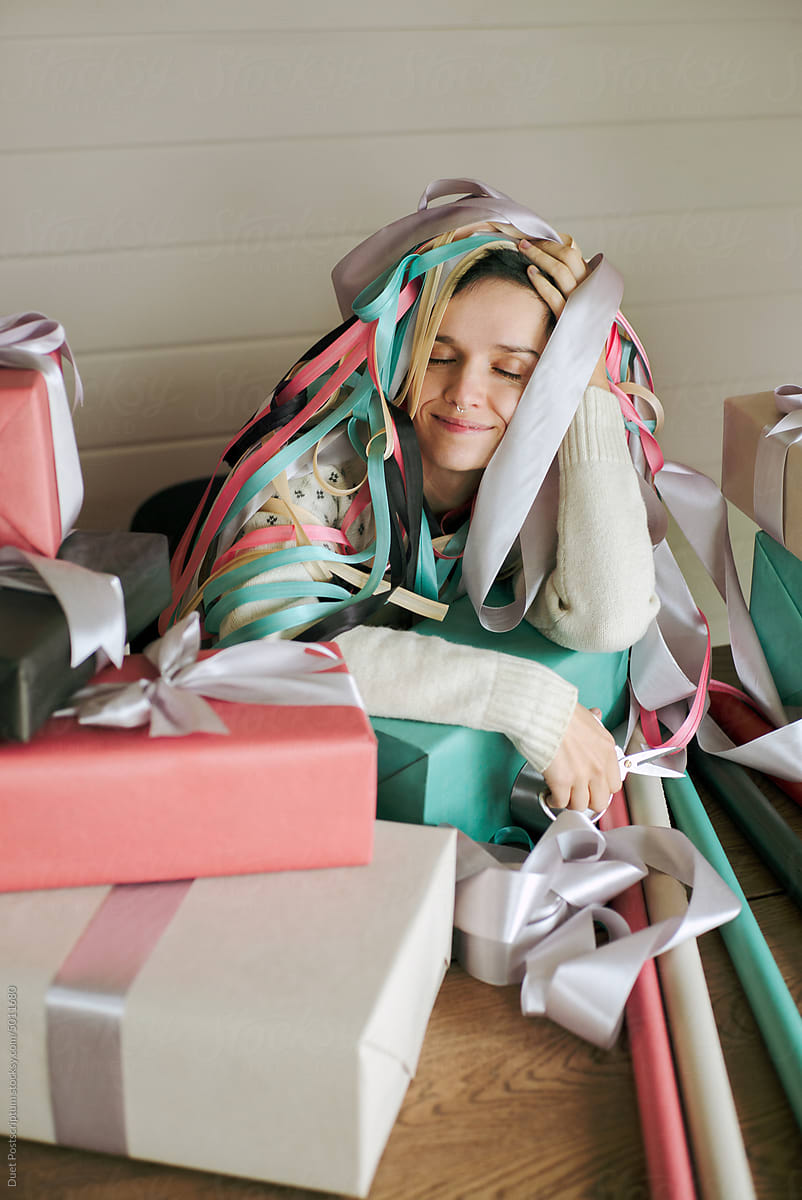 A young woman in a sweater is tired of packing Christmas presents.