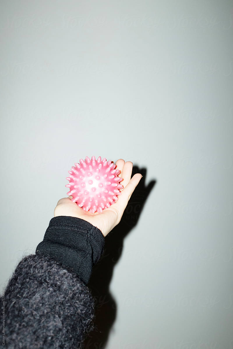 Hand holding a neon pink sport spike ball with hard direct flashlight