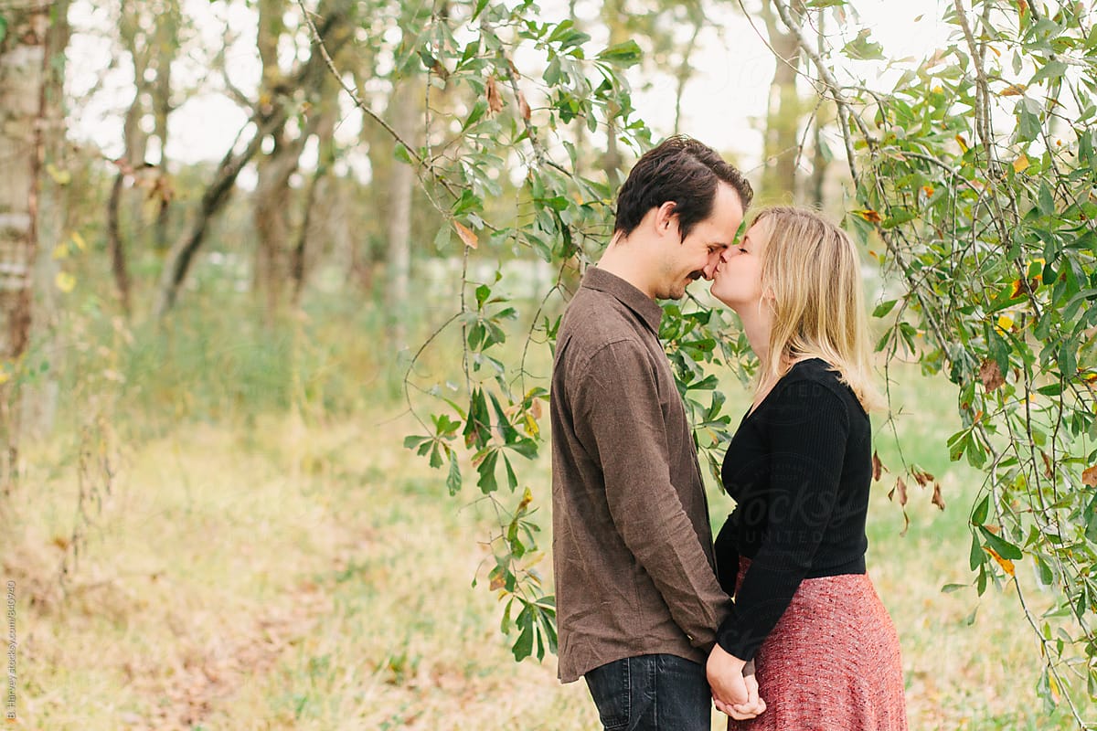 Cute Couple Laughing and Kissing Surrounded by Tree Branches