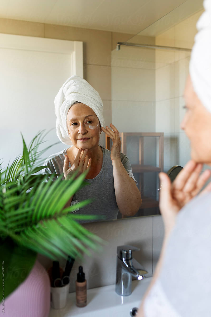 Mature woman looking herself in the bathroom mirror