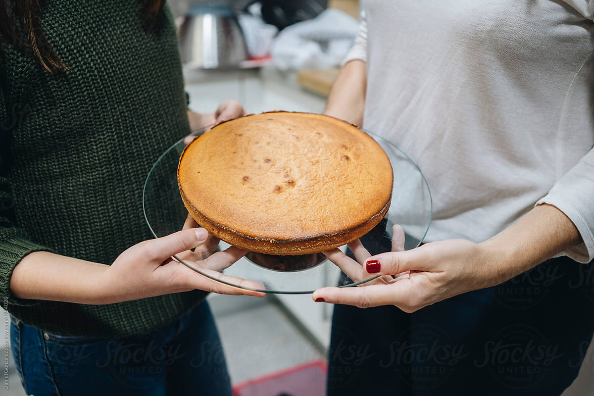 Mom and daughter showing stand with baked cake