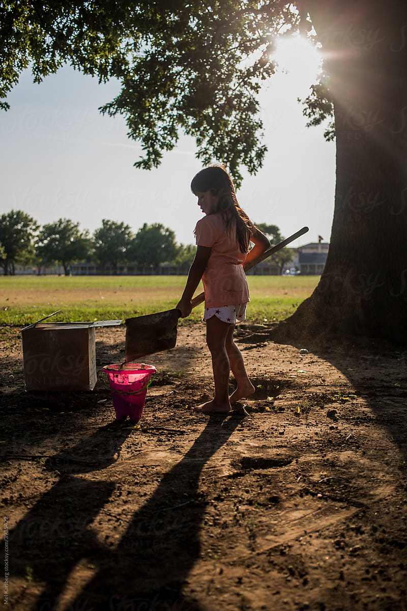 Young girl playing with dirt and bucket in a field