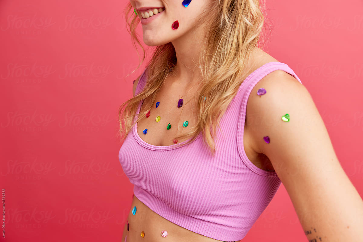Happy lady with colorful gems on body smiling in studio