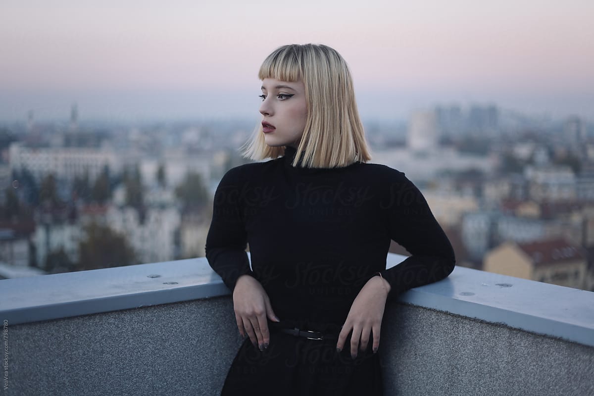Portrait of a beautiful blonde woman on the roof of the building during sunset