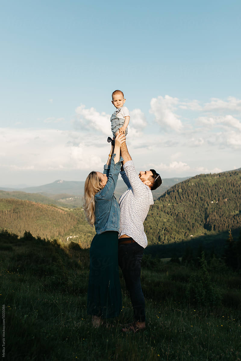 Couple out in nature playing and holding their child
