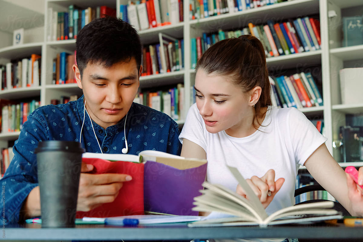 Multiethnic students reading textbook together
