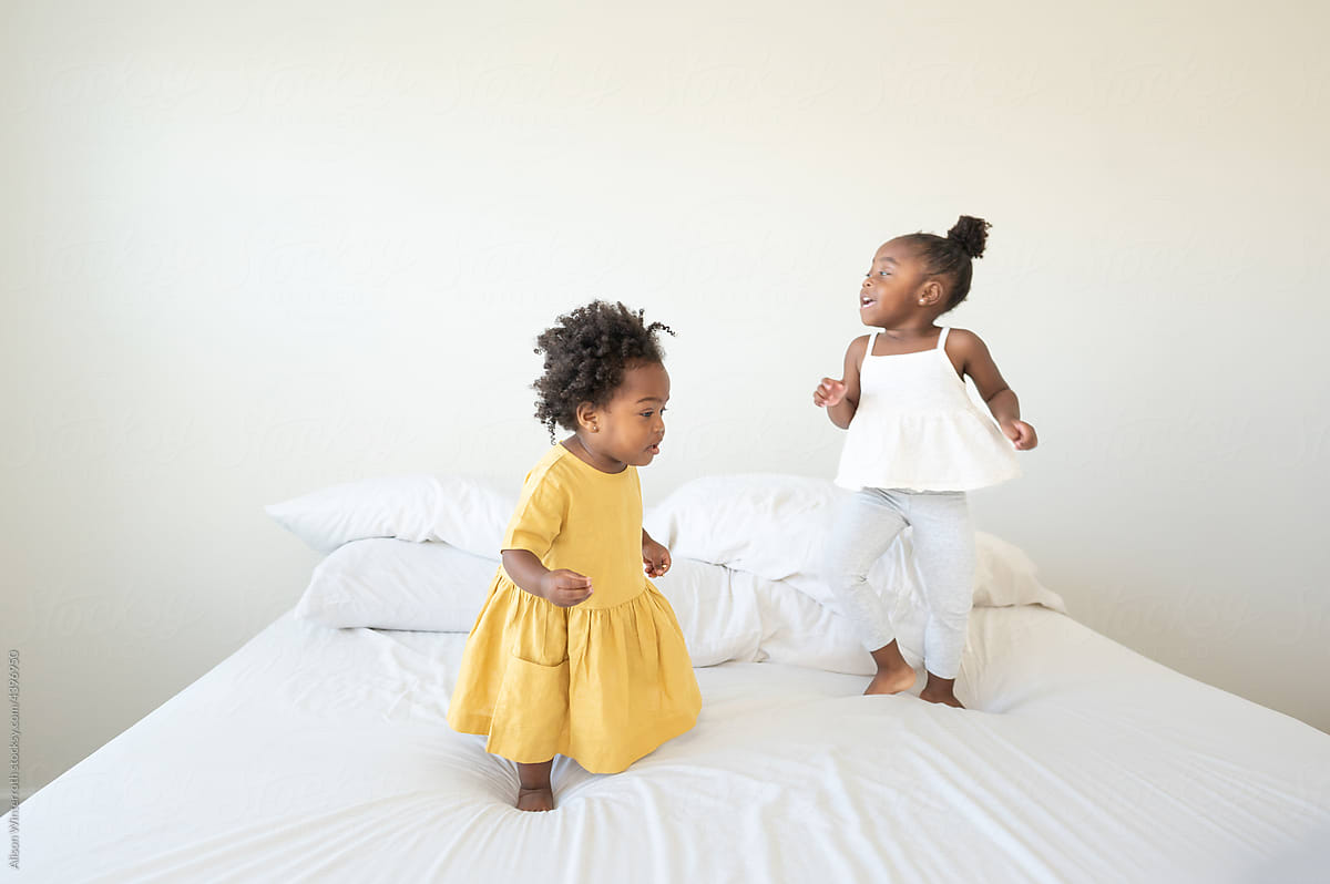 Sisters jumping on a simple bed
