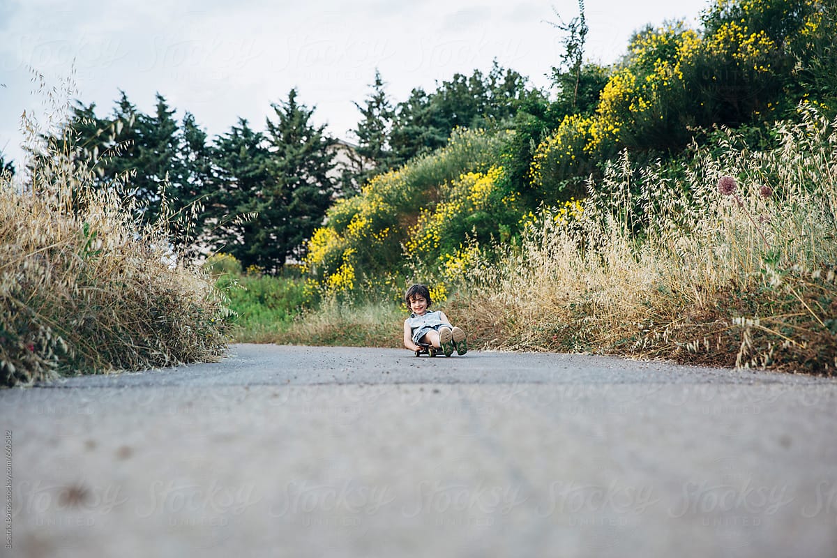 Little boy lying on a skateboard and going ahead on a slight slope