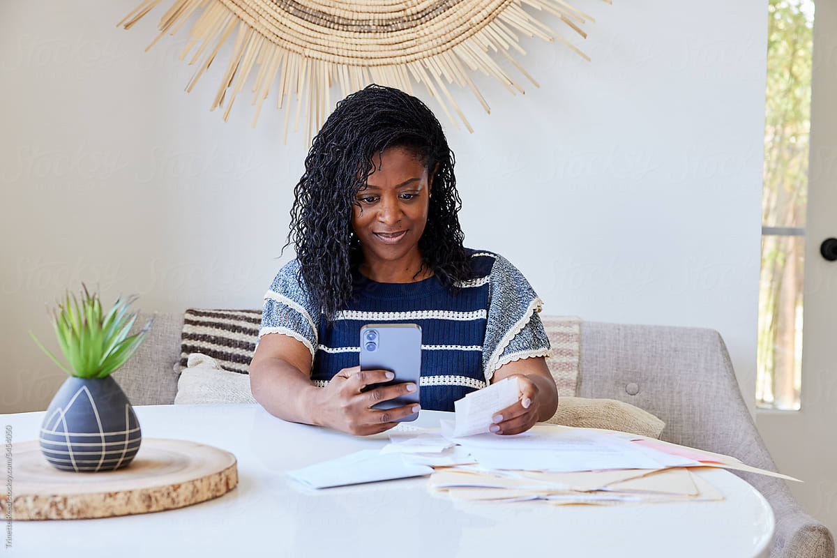 Mature Black woman looking at receipts and finances on phone