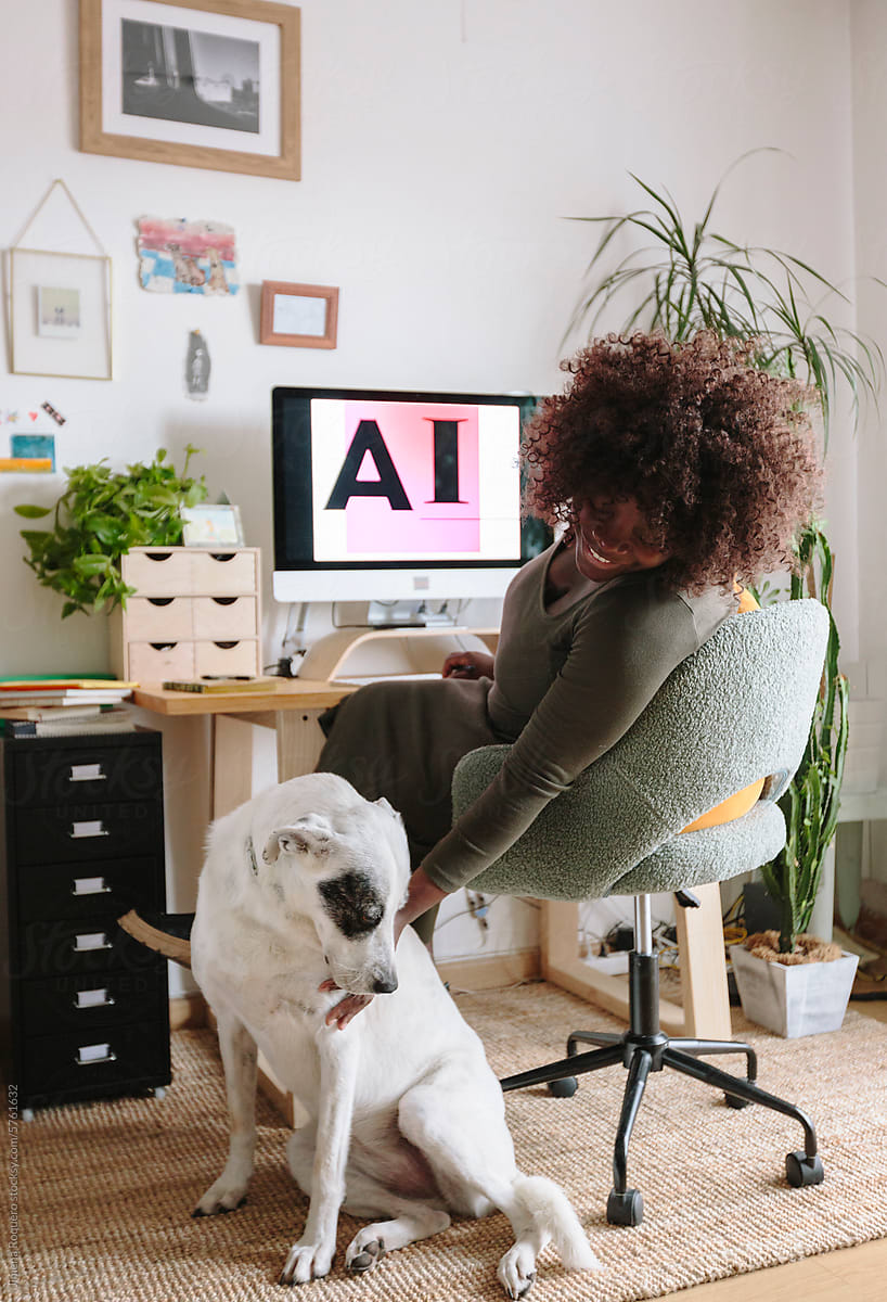 Pregnant designer woman in home office petting her dog