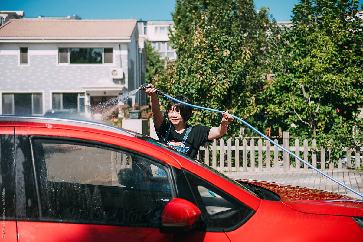 Young woman washing a red car