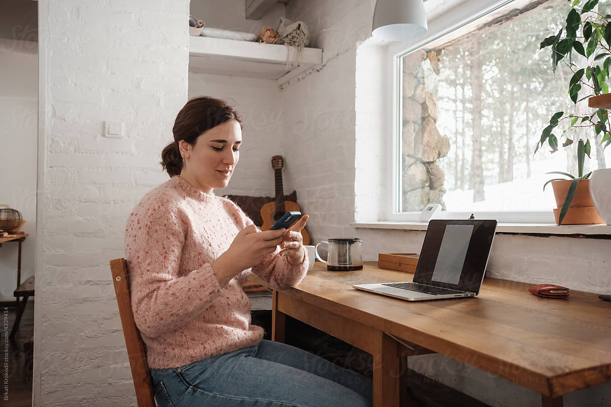 Woman Sitting At Home Office And Looking At The Phone