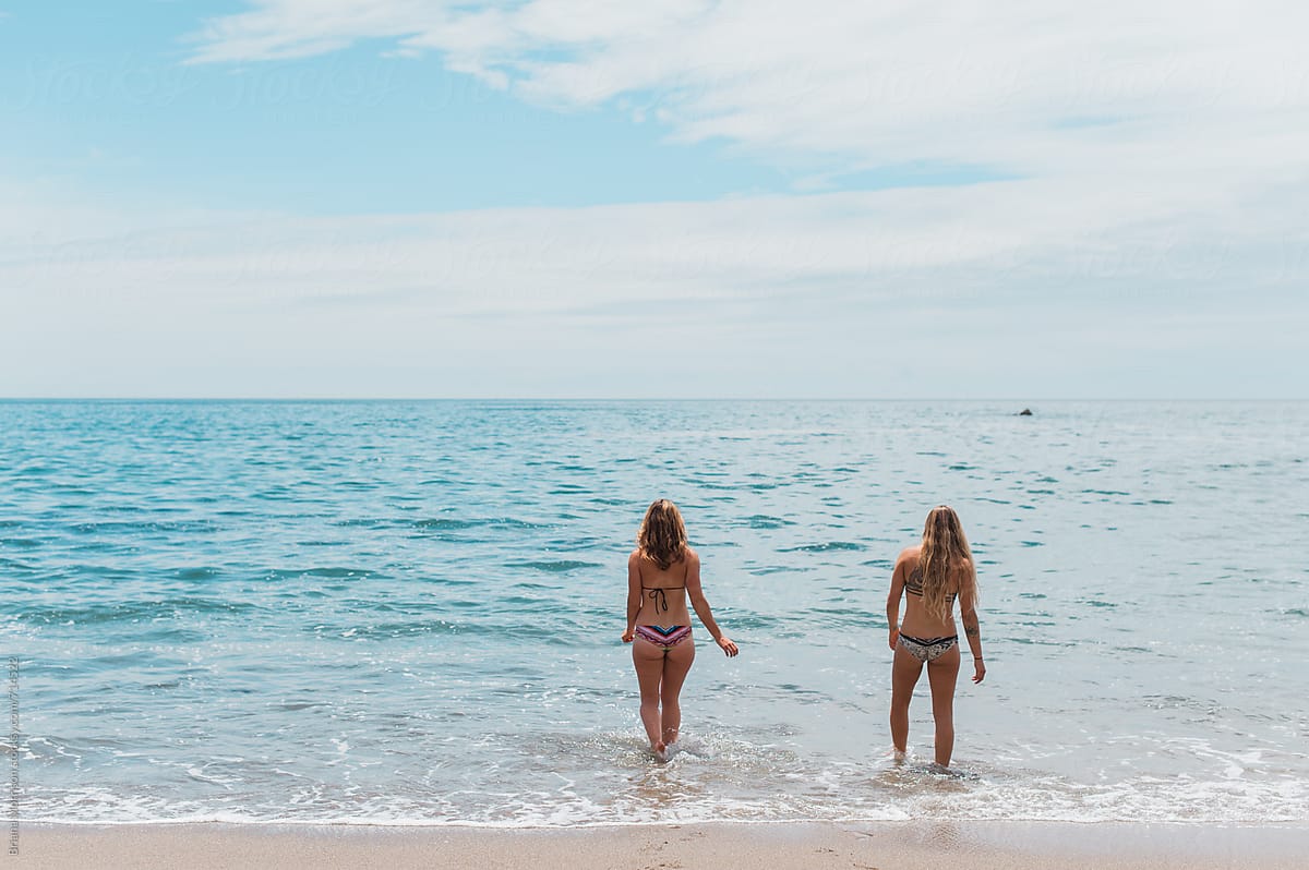 Two Young Women In Bikinis Walking Into The Ocean Together By Stocksy Contributor Briana