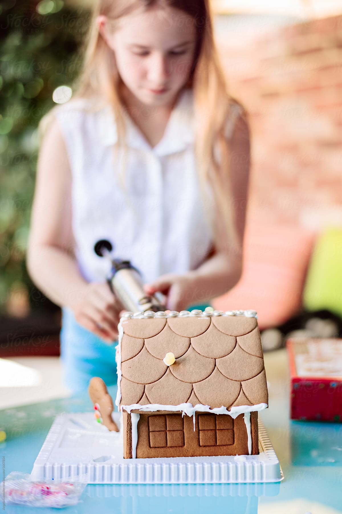 Girl decorating a gingerbread house at christmas