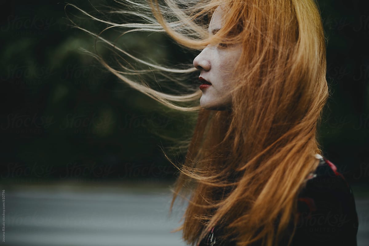 Portrait Of A Ginger Haired Young Woman With Hair Blowing In The Wind