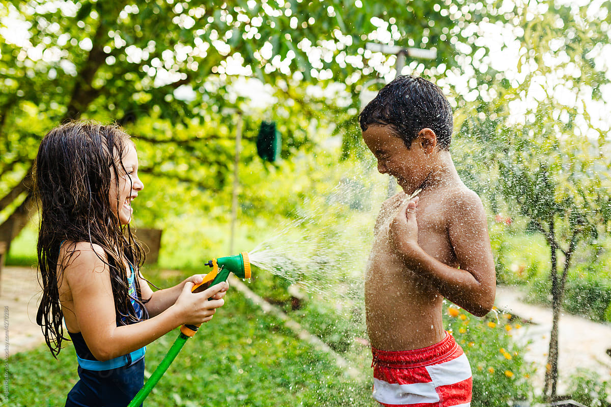 Children playing with hose in the yard, summer refreshment