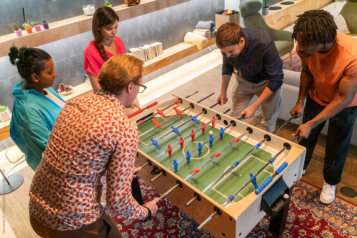 Coworkers Playing Foosball Game At Office
