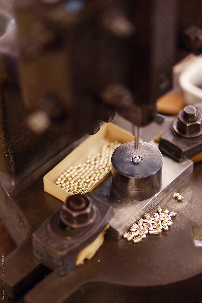 small metal balls are being stamped in a jewellery factory
