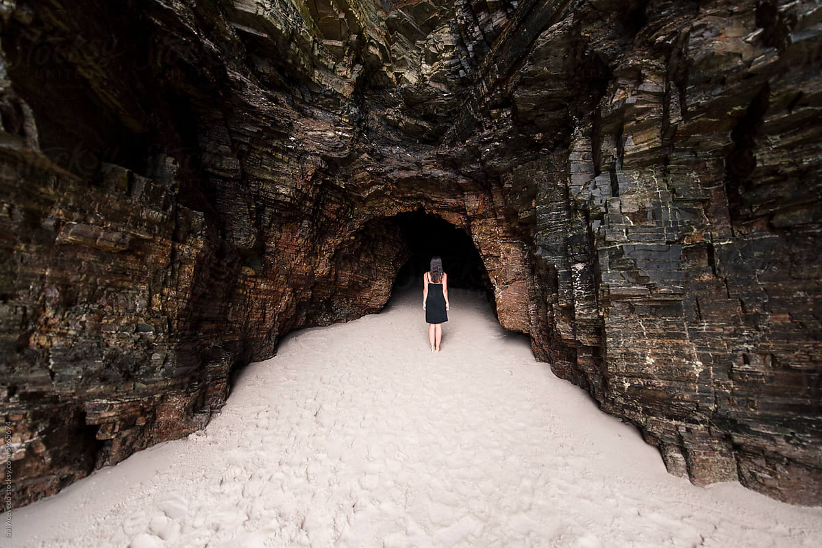 Woman standing on wild beach cave entrance