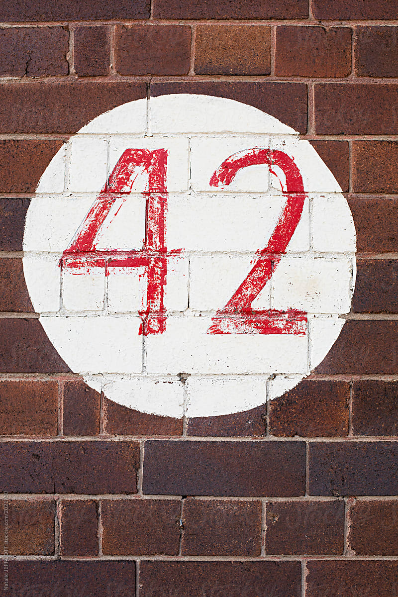 Number 42 painted in red and white on a brick wall