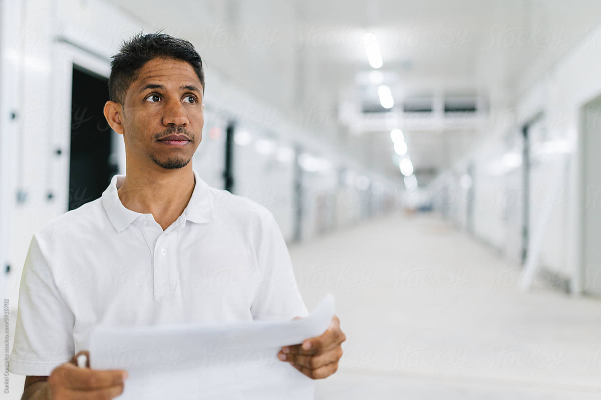 Thoughtful man with papers standing in hallway