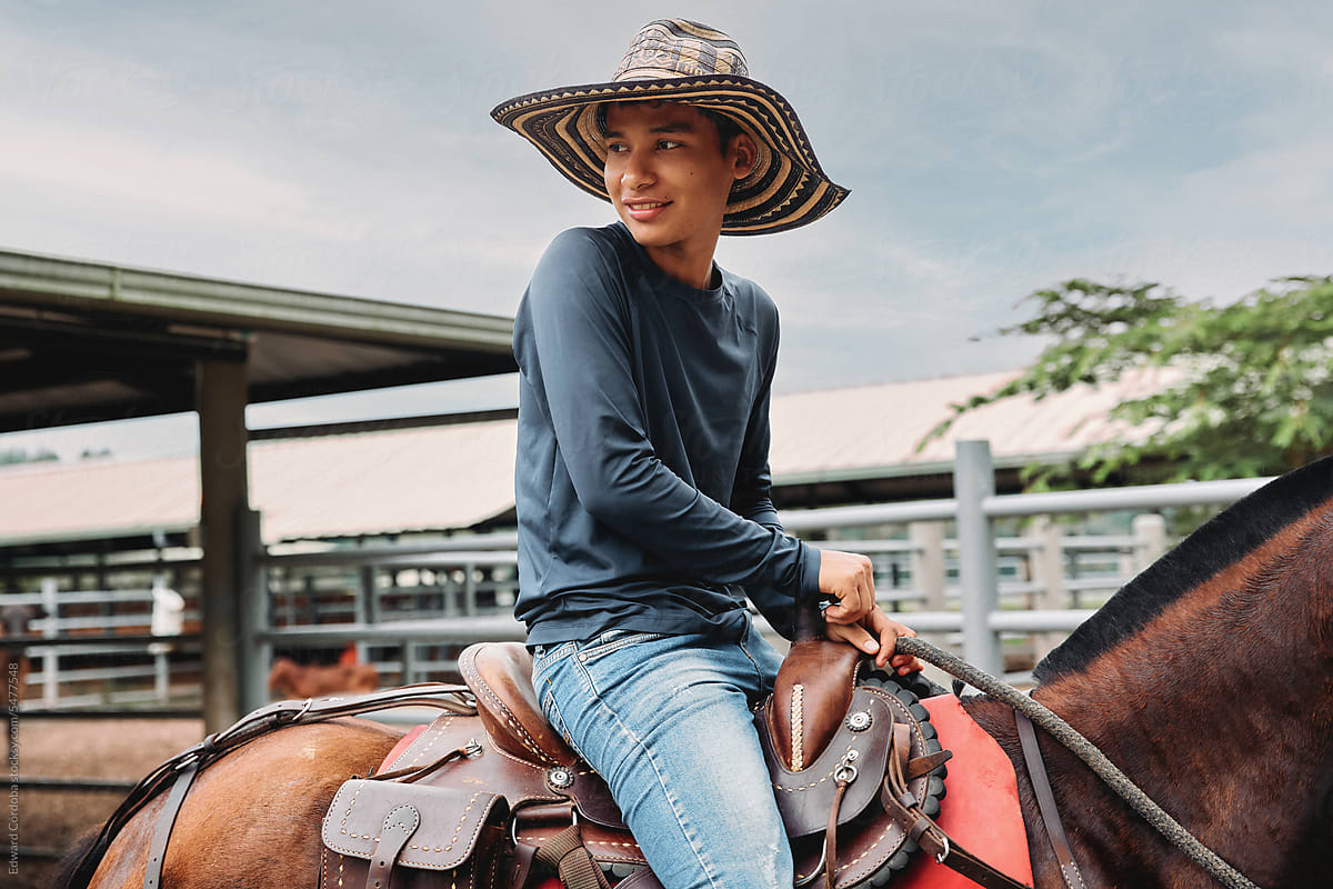 Smiling young cowboy riding on his horse on a Colombian farm