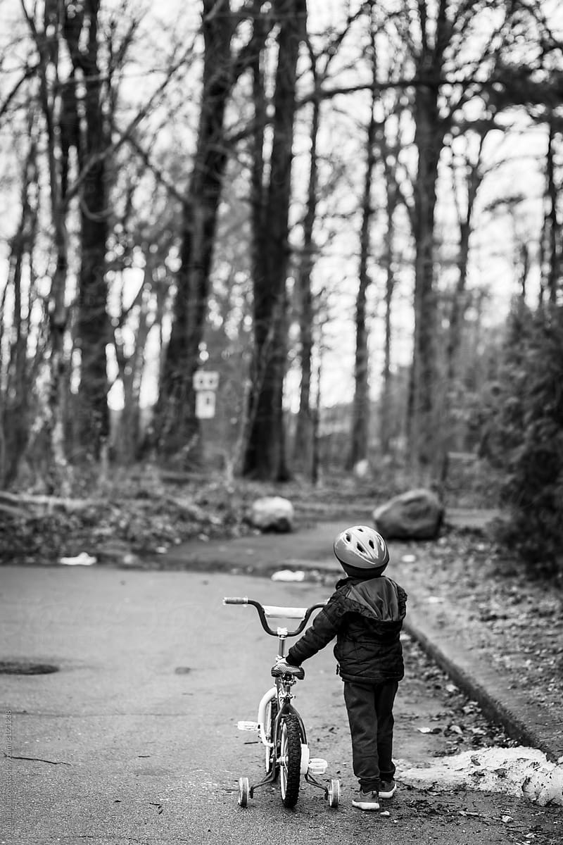 A young boy rides his bike to the park on a suburban street.
