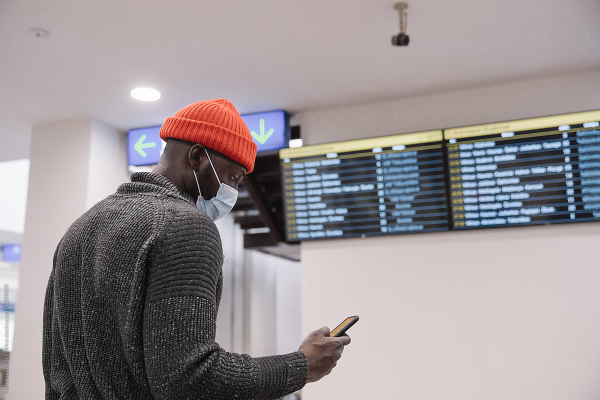 Black Man Wearing Face Mask Using Cellphone At Station