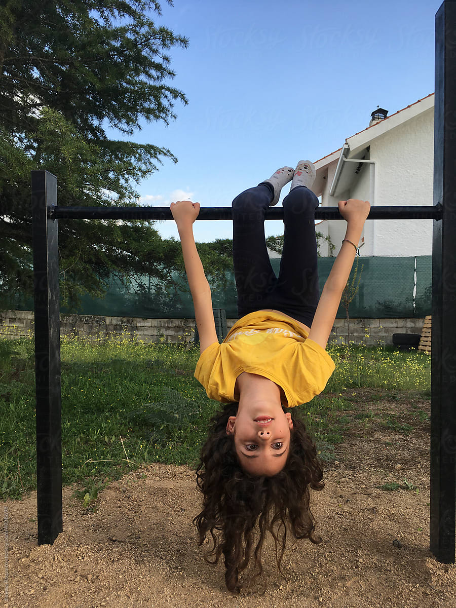 UGC kid hanging upside down from metallic bar in a garden