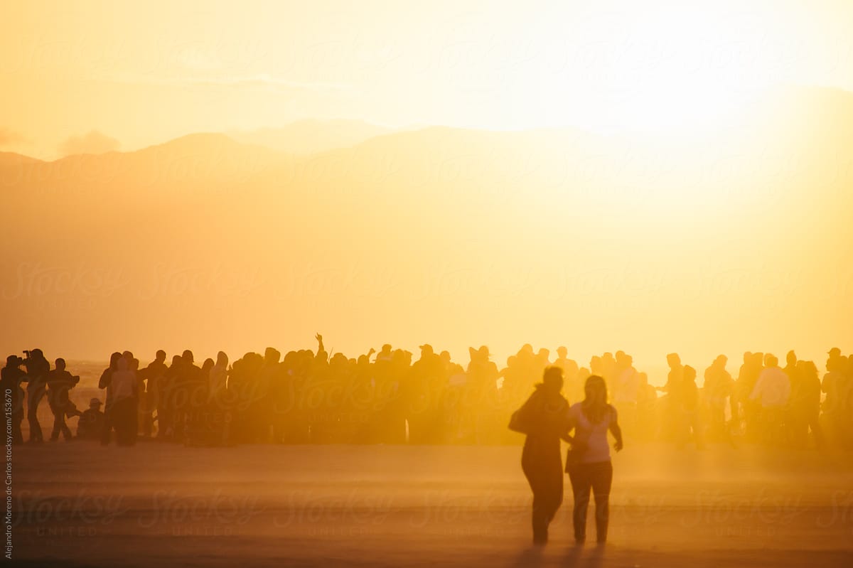 Group of people having fun at the beach on a music concert at sunset. Silhouette people