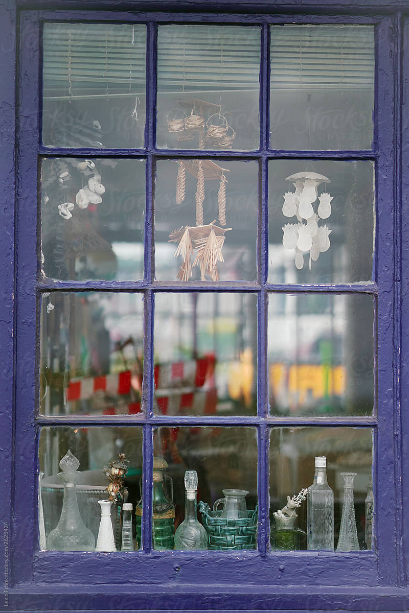 view inside a beach house window with collections of jars and shells inside