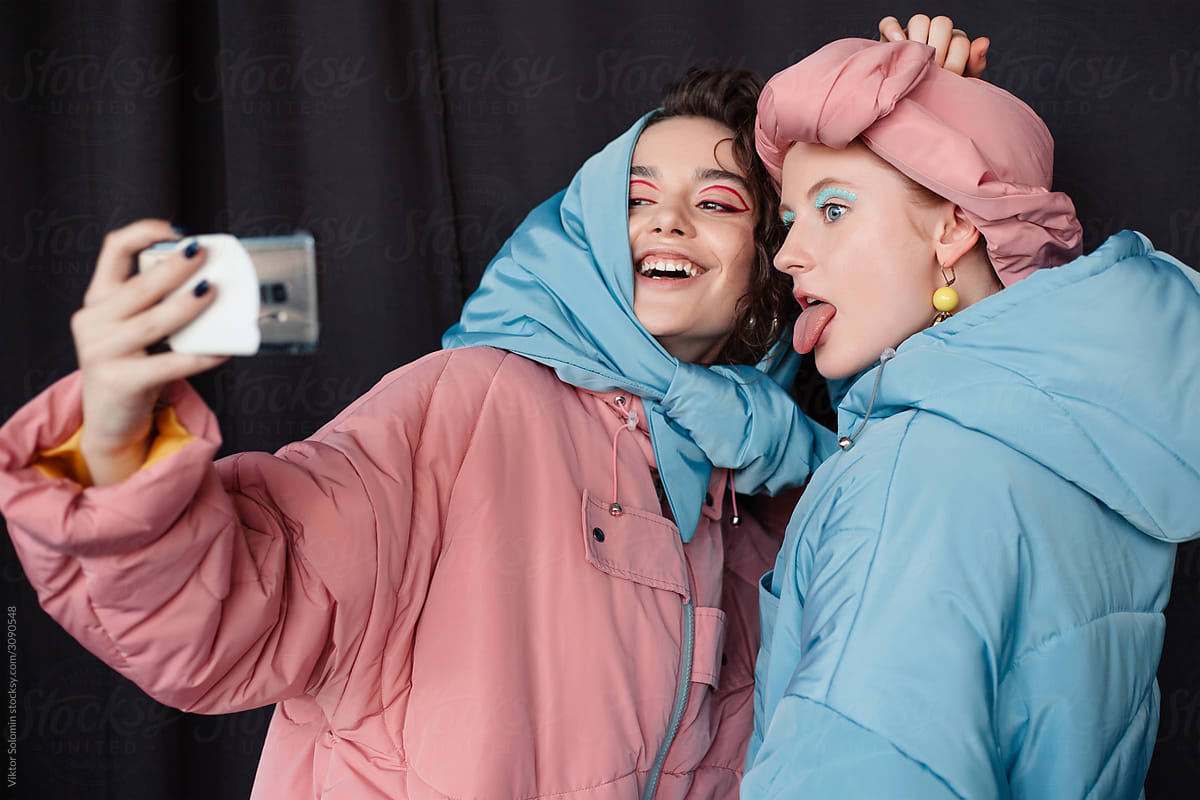 Two cheerful girlfriends with makeup making selfie