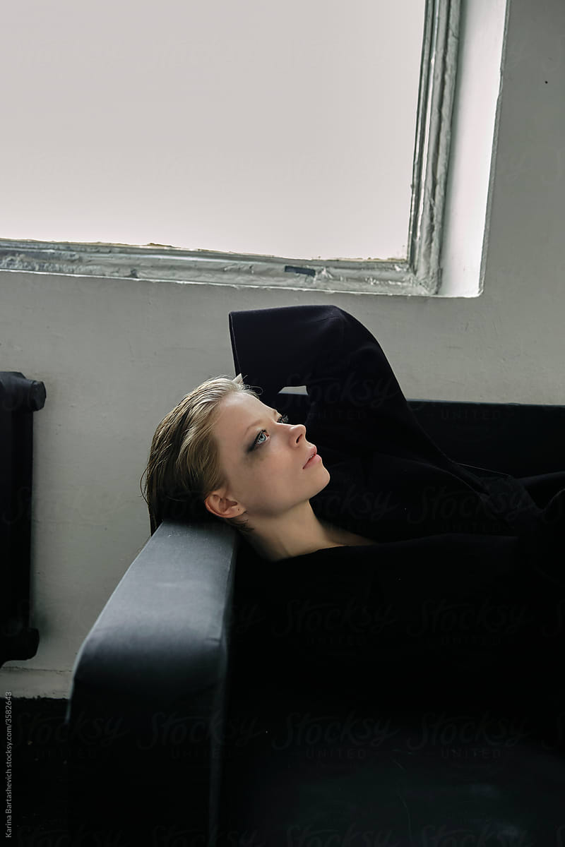 art portrait of a fragile girl with inner strength in profile lying on the back of the sofa