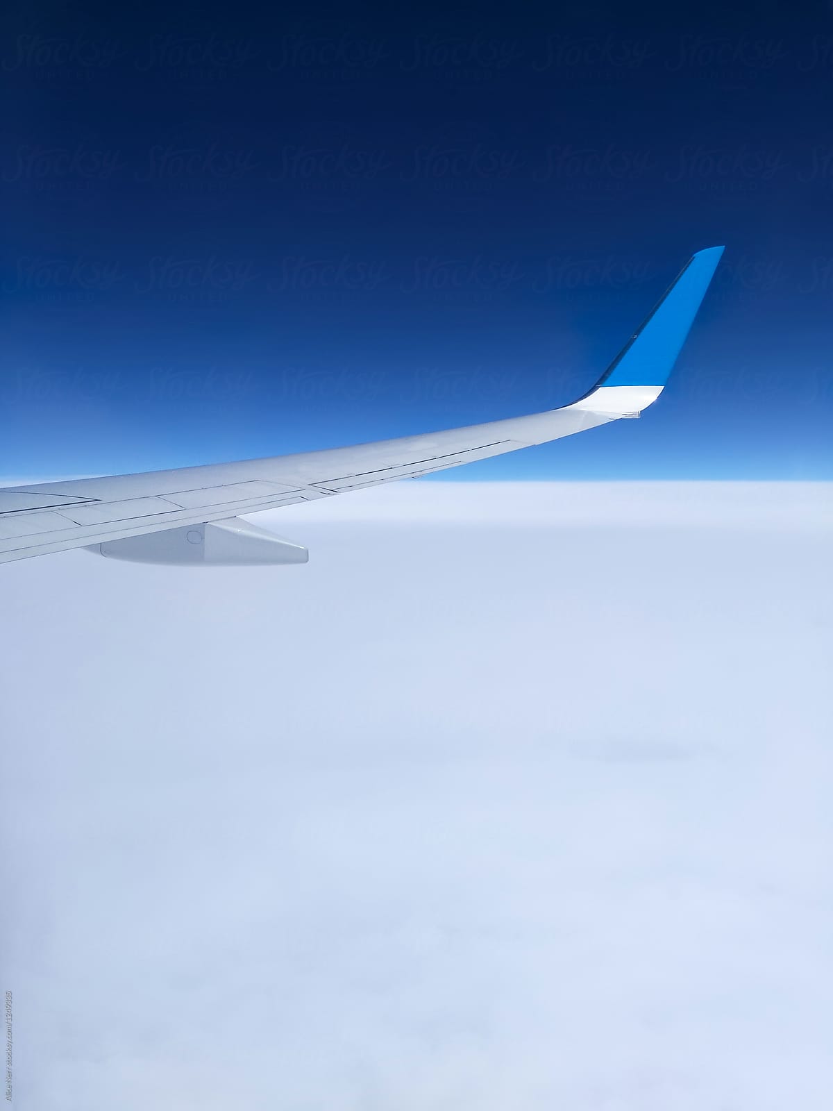 Airplane wing over white clouds