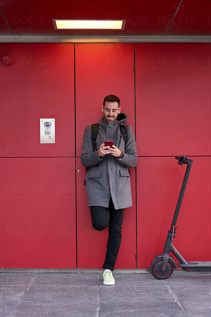 man using smartphone near electric scooter