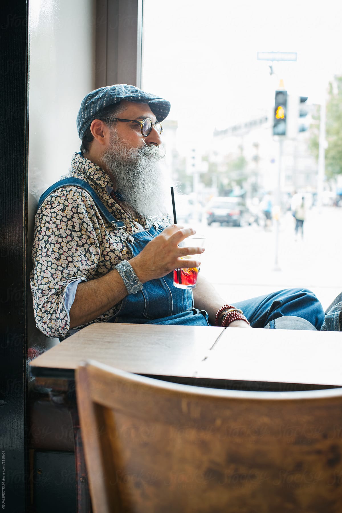 Indoor Portrait of Cool Elderly Male Hipster Enjoying Ice Tea in Restaurant