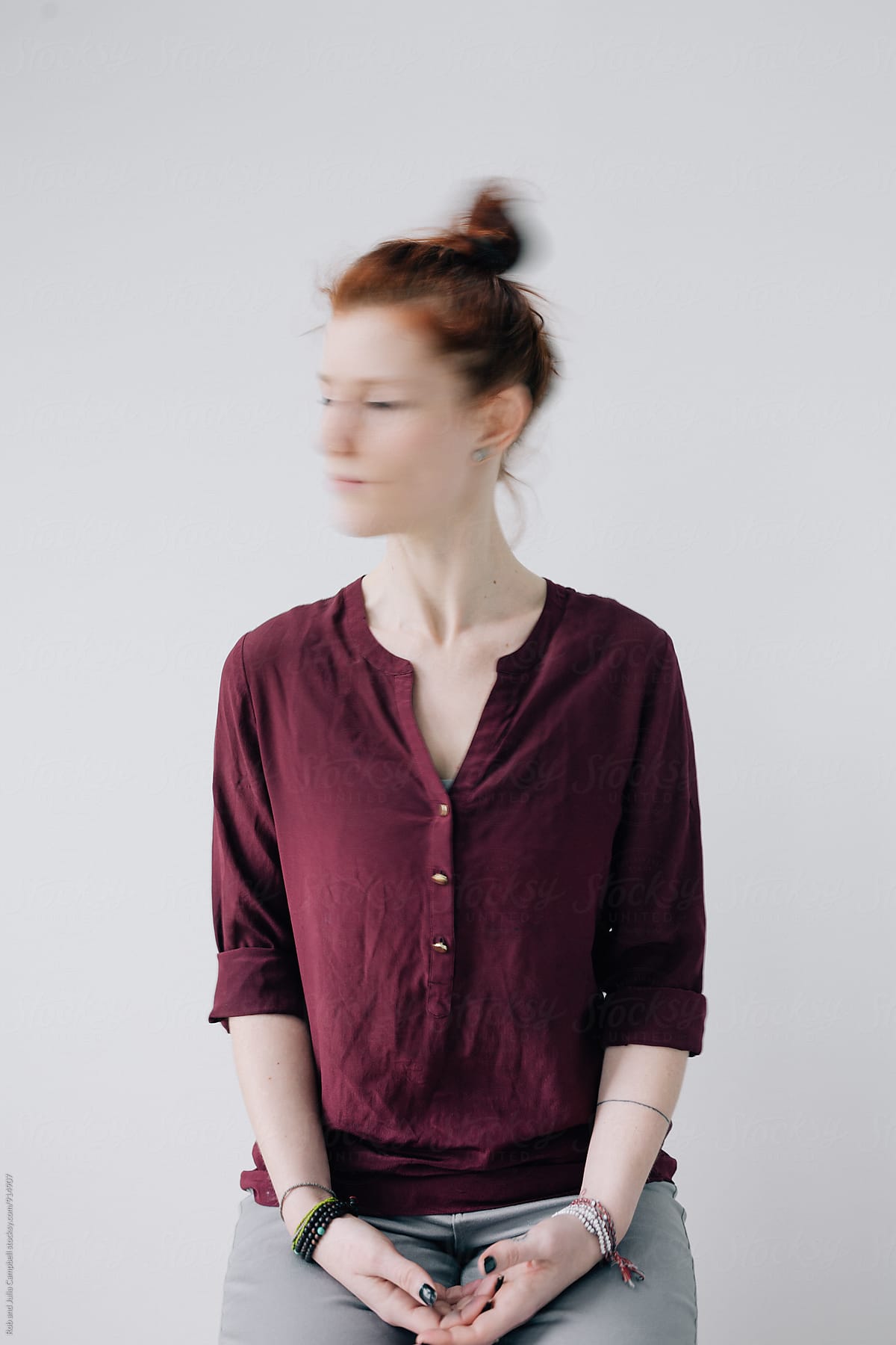 Motion blur portrait of red head woman on simple background